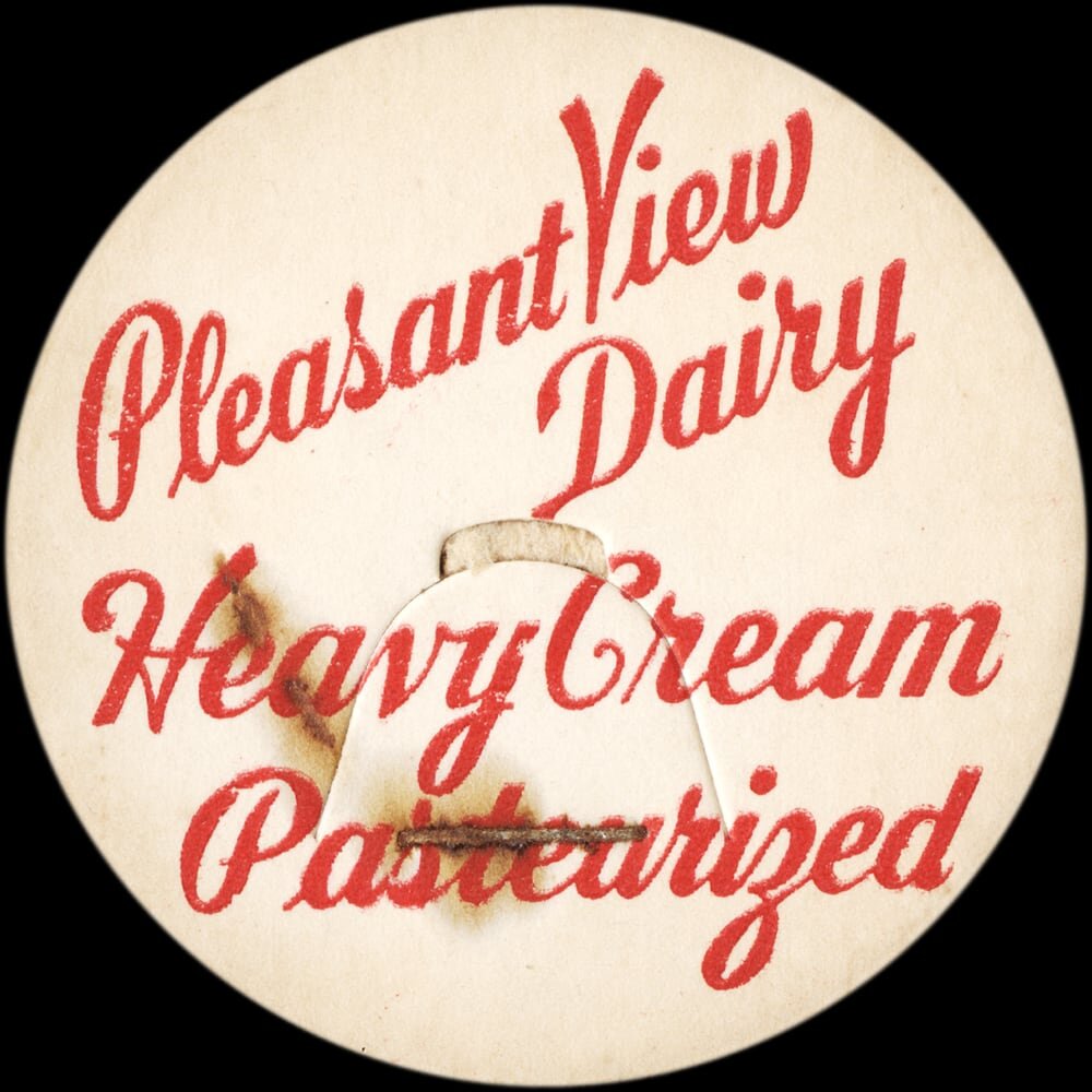Vintage circular dairy cap with printed typographic milk advertising and a metal pull tab.
