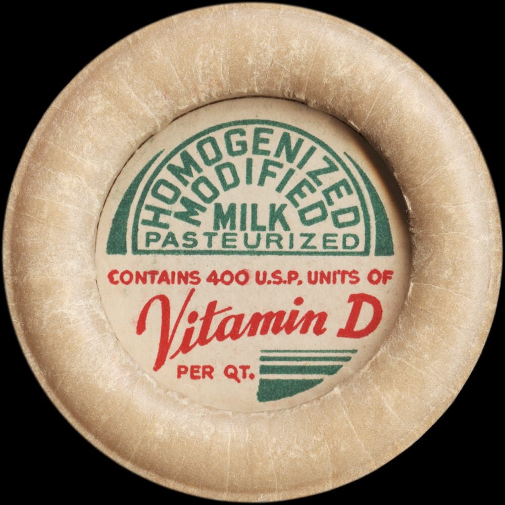 Vintage circular dairy cap with printed typographic milk advertising and a metal pull tab.