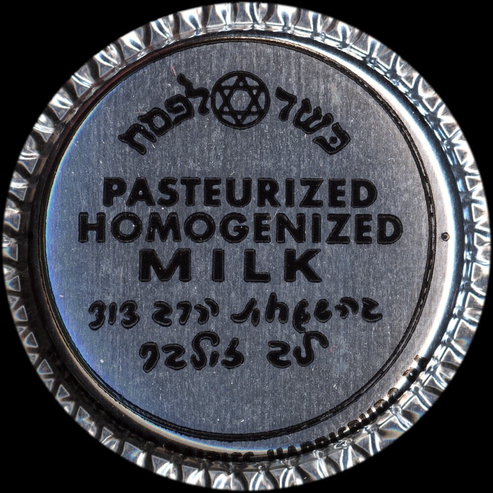 Vintage circular dairy cap with printed typographic milk advertising and a metal pull tab.