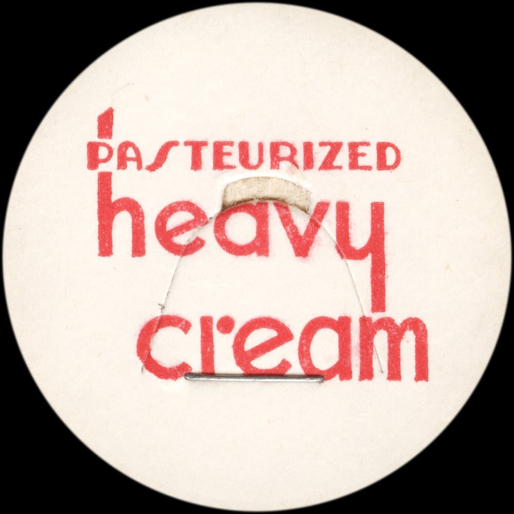 Vintage circular dairy cap with printed typographic milk advertising and a metal pull tab.